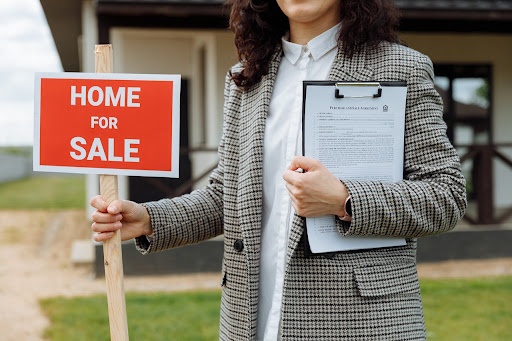 kobieta ze znakiem informującym o mieszkaniu na sprzedaż